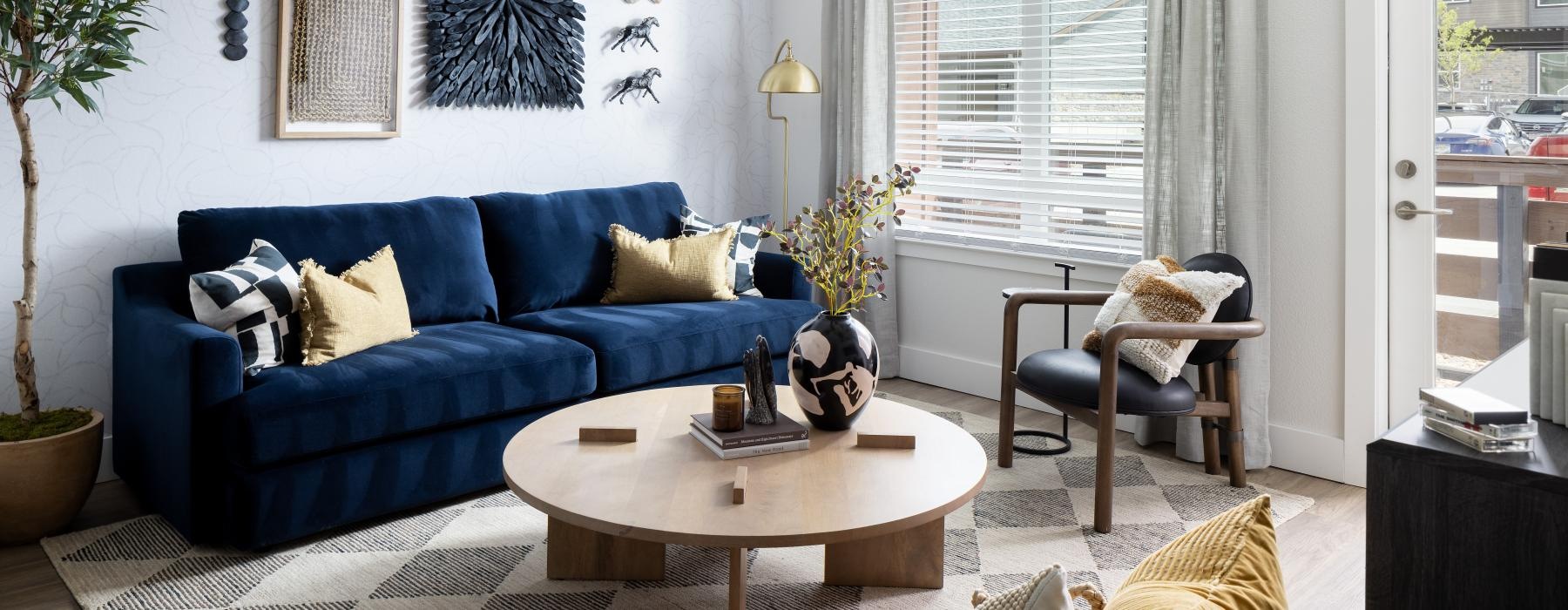 A living room with a blue couch and circle coffee table in our new apartments in Littleton, CO.